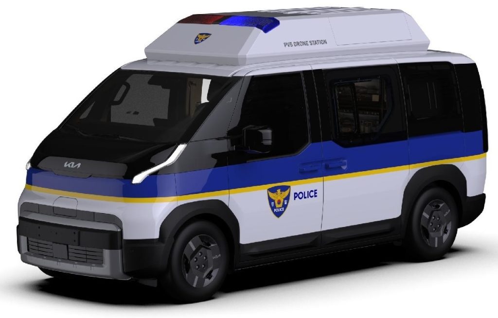 Police van with blue stripe, yellow trim, and a drone station on the roof.
