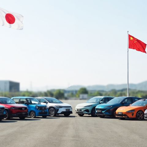 Row of colorful electric cars parked in an outdoor lot with the Japanese, Chinese, and American flags waving above the scene.