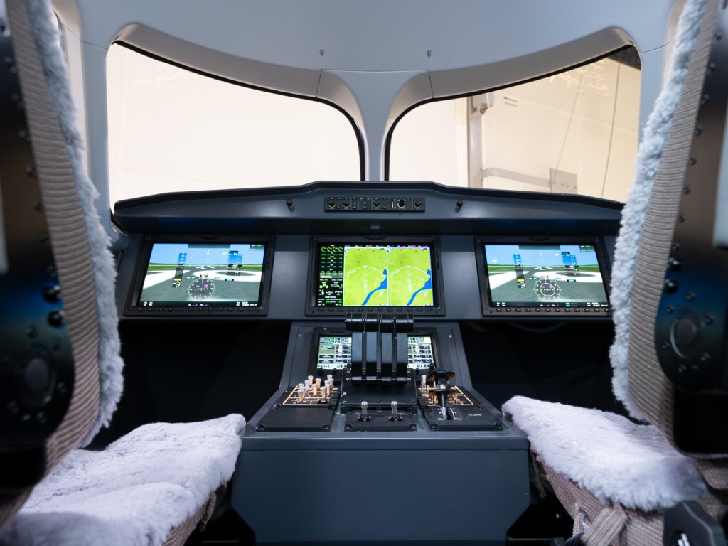 Cockpit interior with three main screens showing flight instruments and a central throttle quadrant.